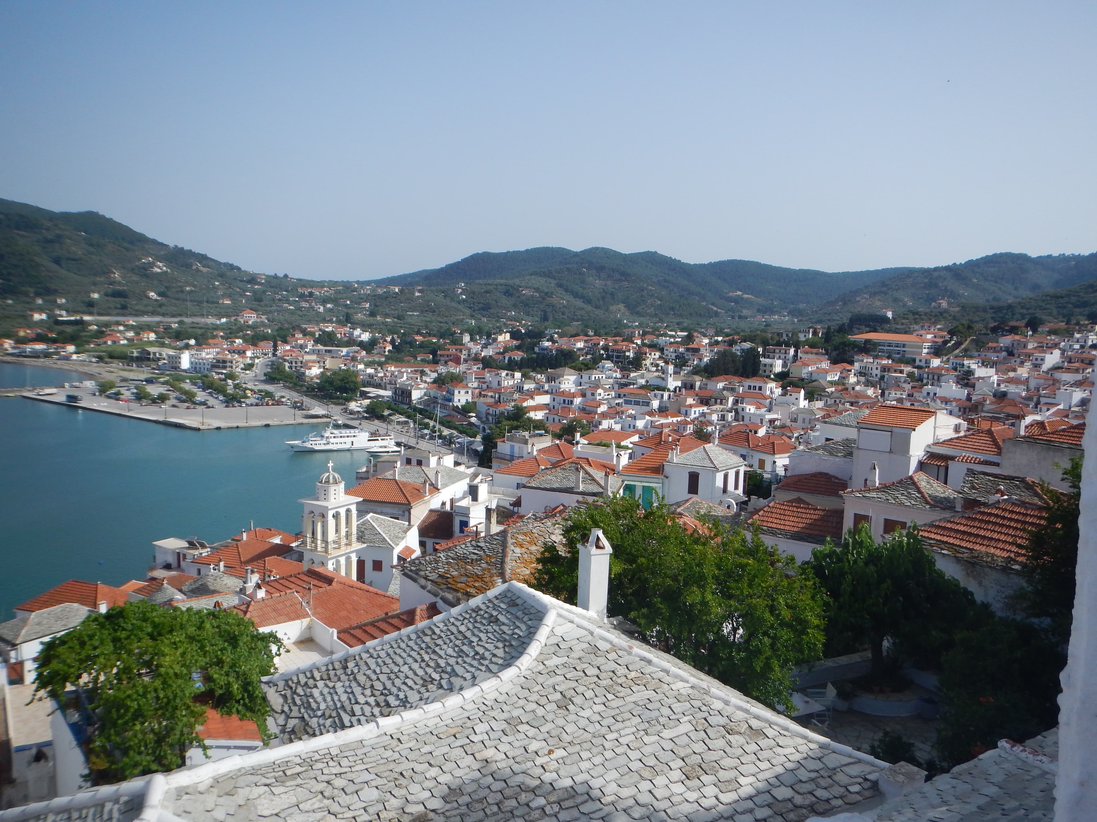 Photo: Chris Taklis, CC BY-SA 4.0, via Wikimedia Commons (https://commons.wikimedia.org/wiki/File:Panoramic_view_of_Skopelos_city.jpg)